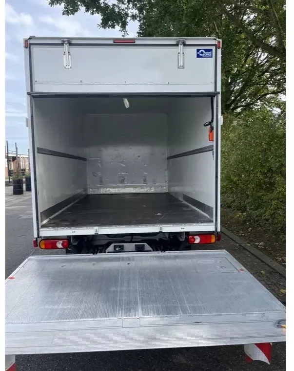 Vue arrière d’un camion fermé blanc, porte ouverte sur l’intérieur vide, hayon élévateur abaissé au sol.